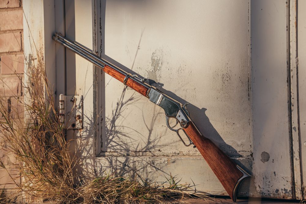 Replica winchester rifle leaning on a doorframe. Picture taken outside. 