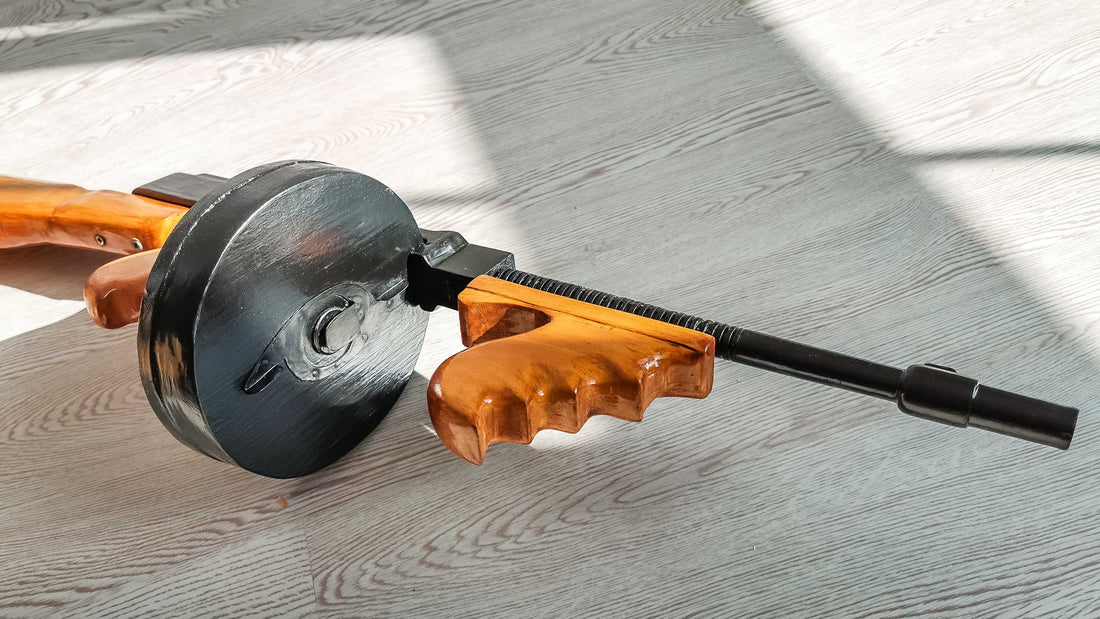 Replica Thompson submachine gun with wooden stock and drum magazine displayed on a wooden floor.