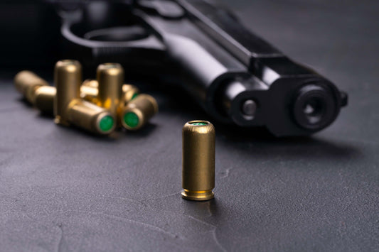 Close-up of a handgun and bullets on a dark surface