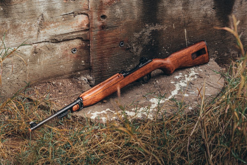 Side view of rifle in the forest on the ground. 