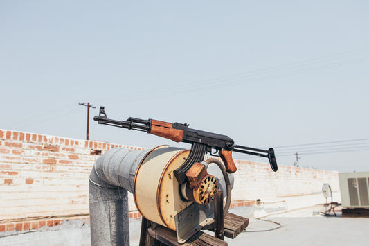 AK-47 with folding stock side view on top of a pipe.