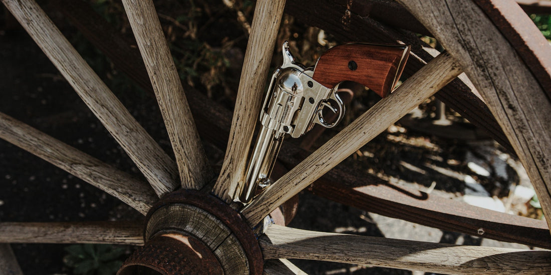 Old west fast draw revolver with nickel finish displayed in an old wooden wagon wheel. 
