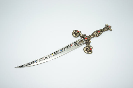Spanish dagger with brass pommel and grip and red encrusted jewels . Detailed blade out of sheath.